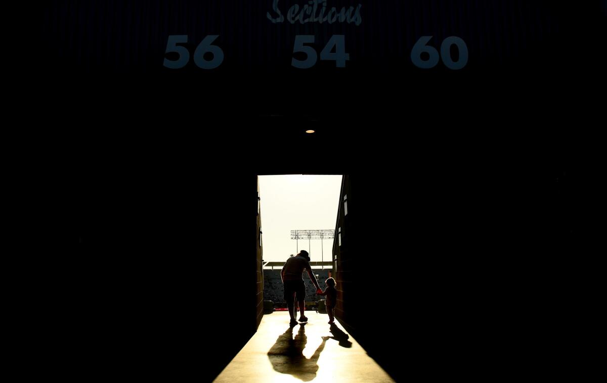 A father takes hold of his son as they walk to their seats at Dodger Stadium. (Wally Skalij / Los Angeles Times)