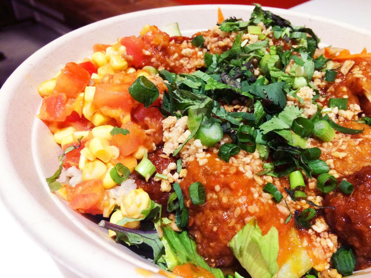 A bowl from Kaya Street Kitchen with shrimp and pork meatballs, corn sambal, green onions, brown rice, kale and more.