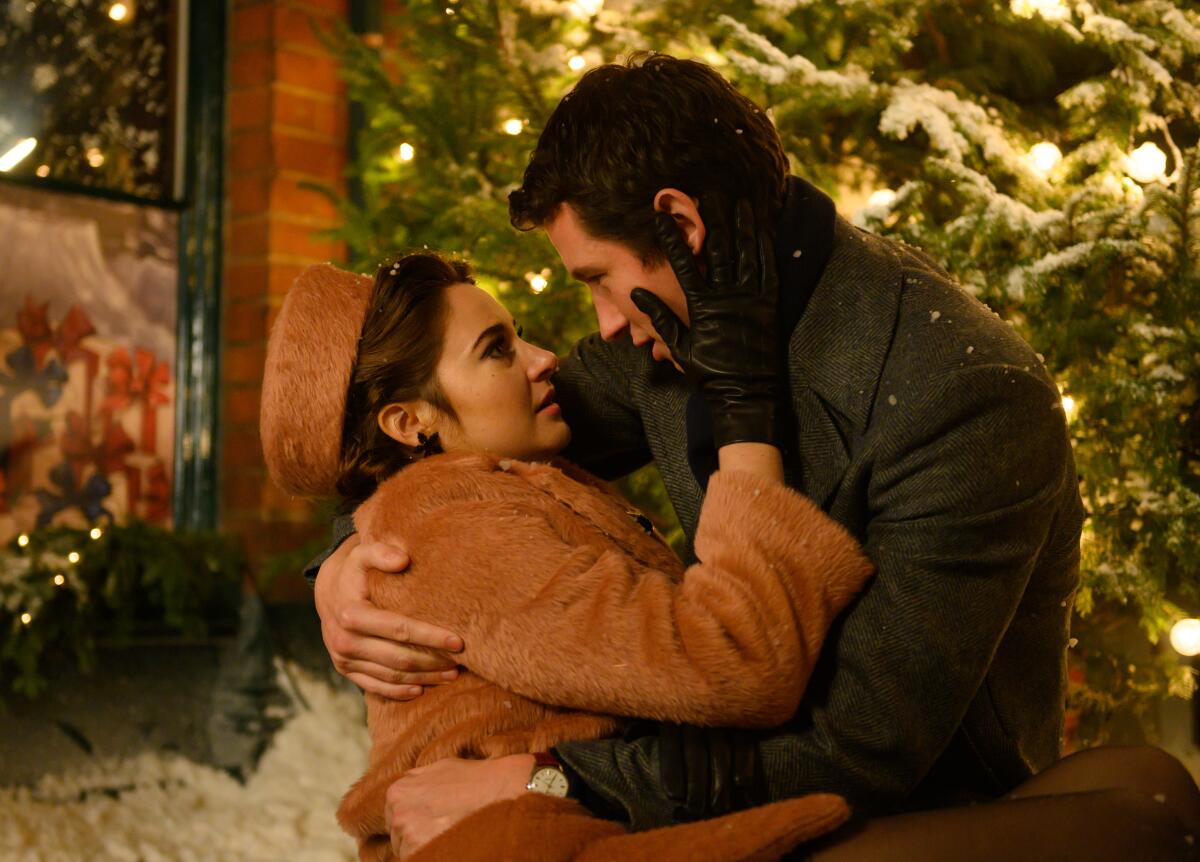 A man and a woman embrace in front of Christmas decorations.