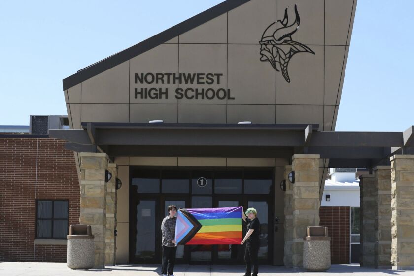 FILE - Former Viking Saga student newspaper staff members Marcus Pennell, left, and Emma Smith display a pride flag outside of Northwest High School in Grand Island, Neb., July 20, 2022. A former high school journalist is suing the Nebraska school district that last year shut down the school newspaper after it published an LGBTQ-focused edition. The federal lawsuit filed Friday, March 31, 2023, names Grand Island Northwest Public Schools and its superintendent. It claims the shutdown of the student paper at Northwest High School was unconstitutional. (McKenna Lamoree/The Independent via AP, File)