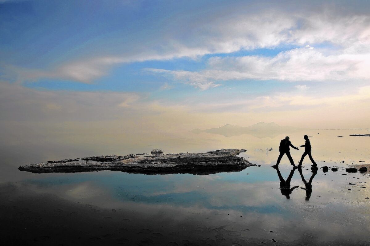 Two men walk toward salt-covered rocks that were once deep underwater at Lake Urmia, in northwestern Iran. Experts say that in the last two decades, a toxic combination of wasteful irrigation practices, the damming of feeder rivers, prolonged drought and a warming climate has accelerated the decline of the storied lake.