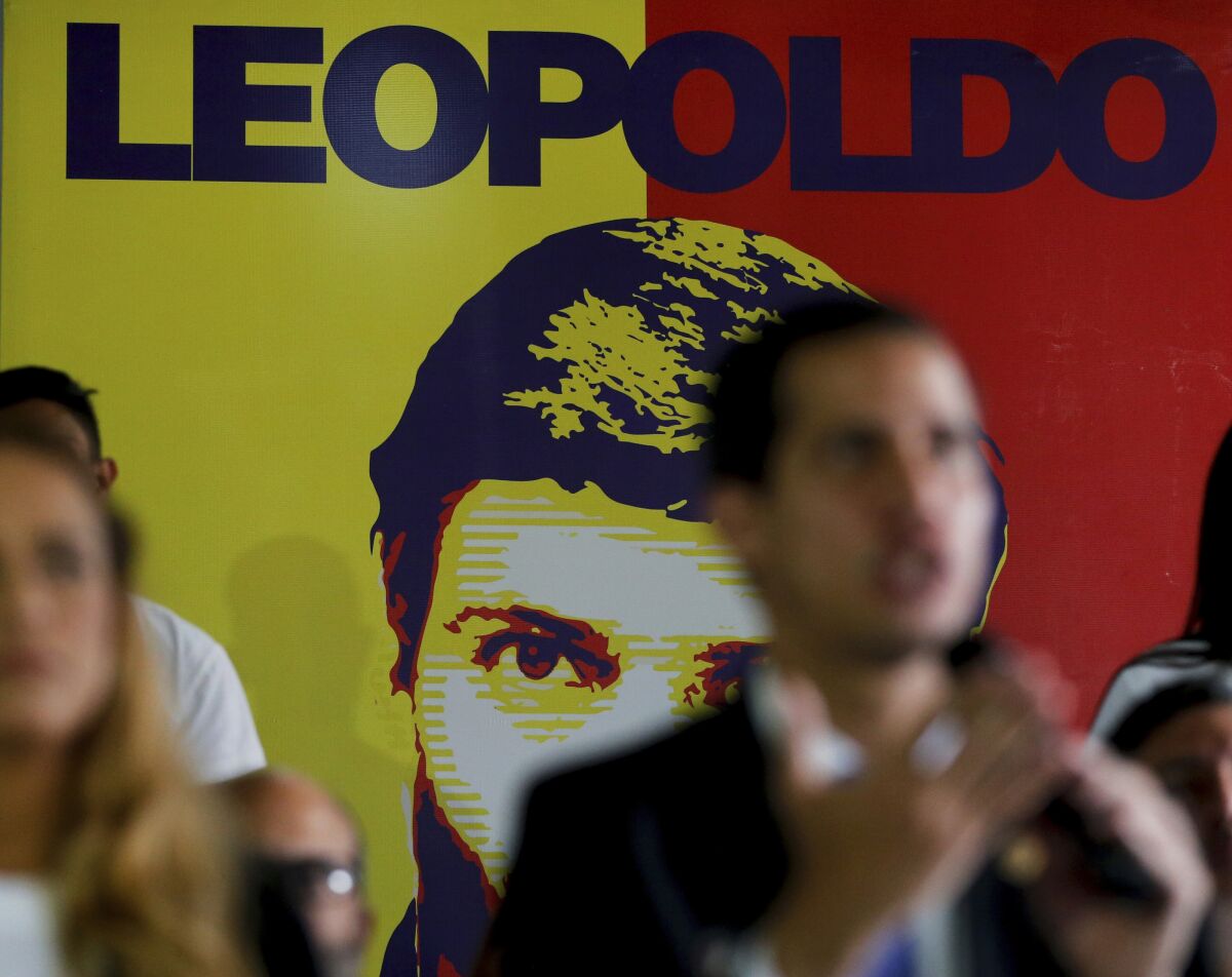 FILE - In this Feb. 18, 2019 file photo, Venezuela's self-proclaimed interim president Juan Guaido speaks during a news conference at the Popular Will party headquarters, backdropped by a banner featuring party founder and opposition leader Leopoldo Lopez, in Caracas, Venezuela. Venezuela’s government-stacked Supreme Court ordered the takeover of Popular Will Tuesday, July 7, 2020, the latest in a series of moves against President Nicolas Maduro’s critics before upcoming legislative elections. (AP Photo/Fernando Llano, File)