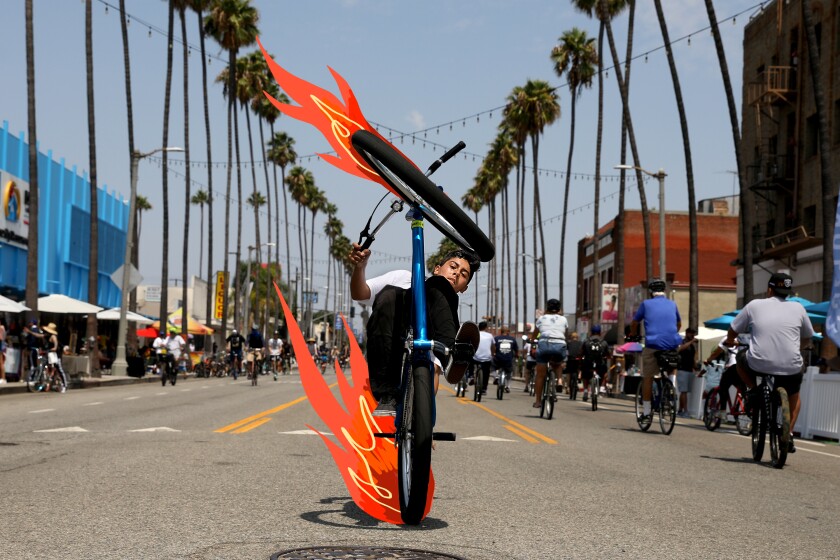 A person on a bike performs a wheelie with illustrated flames on the tires.