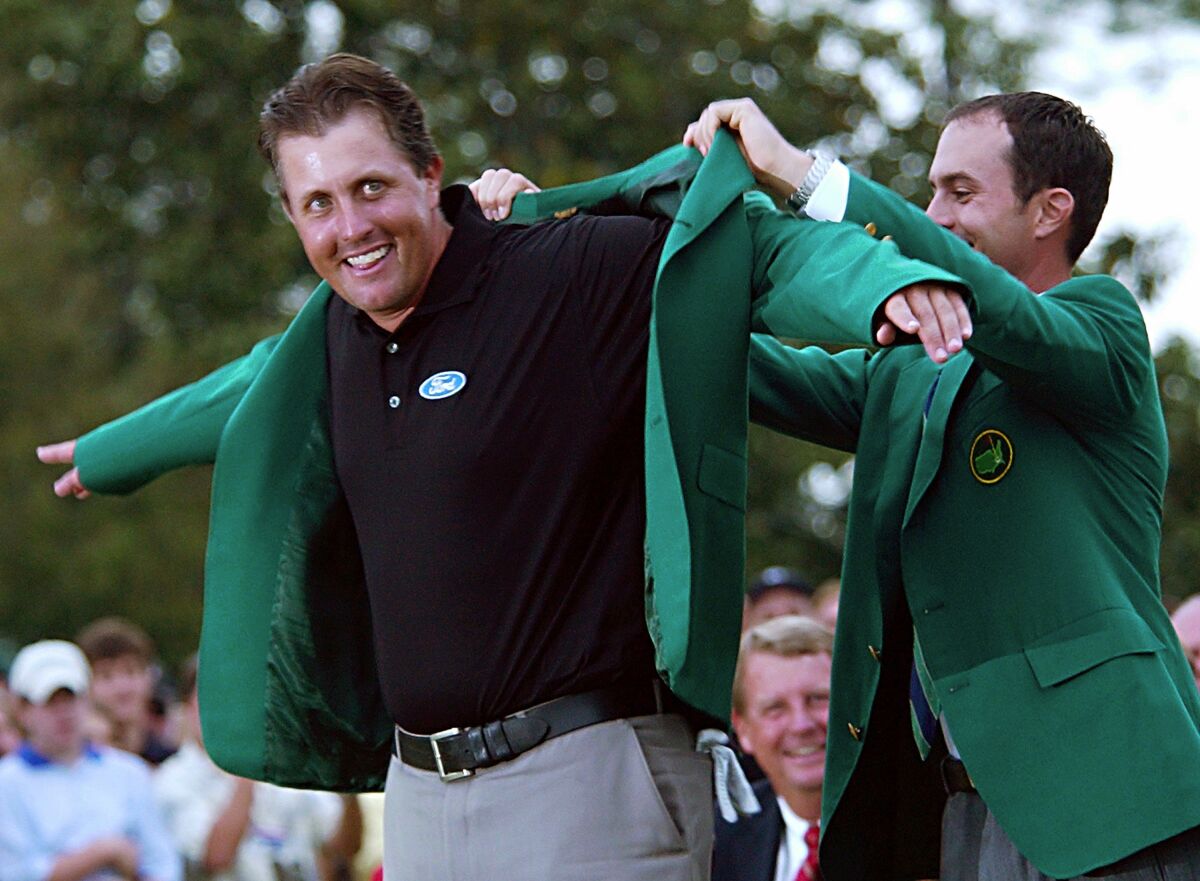 Mike Weir helps Phil Mickelson put on the iconic green jacket following Mickelson's win at the Masters in 2004.