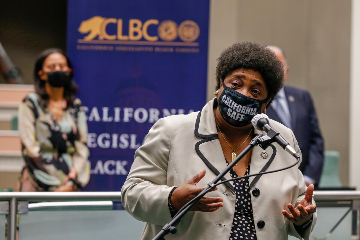 Shirley Weber, now California’s secretary of state, wears a "California safe" mask while speaking into a microphone 