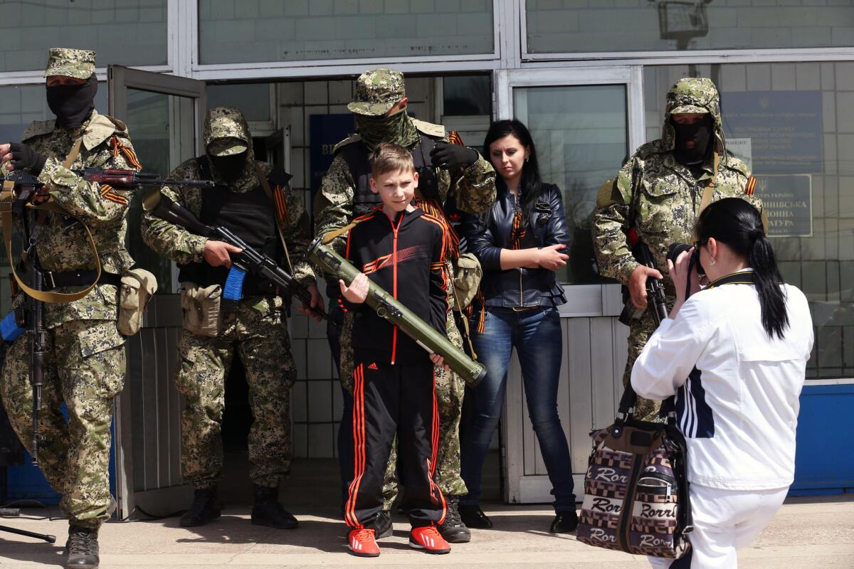 Yelena Khodyreva takes a picture of her 12-year-old son, Ivan, holding a grenade launcher handed to him by masked separatists in the Ukrainian city of Kostiantynivka.