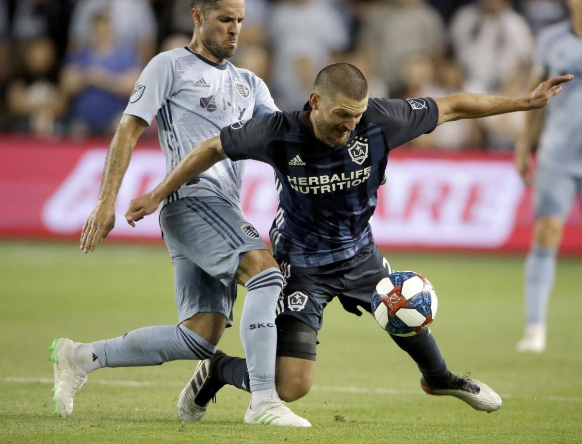 Sporting Kansas City midfielder Benny Feilhaber, left, and Galaxy defender Perry Kitchen chase the ball May 29 in Kansas City, Kan.