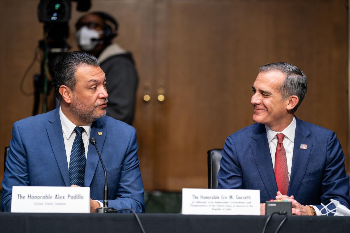 Two men sitting at a table look at each other.