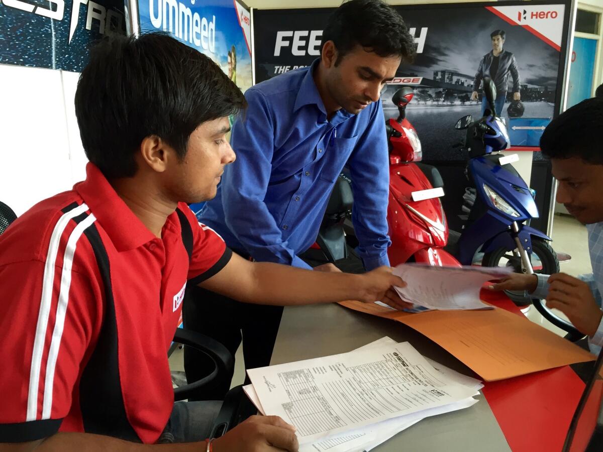 Vikesh Shukla, left, helps manage a busy motorcycle showroom, a symbol of India's fast-growing economy.