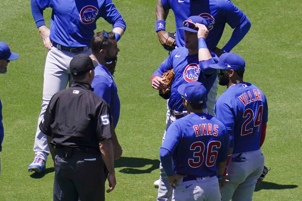 Chicago Cubs shortstop Nico Hoerner, above right, talks with a trainer after injuring himself when he collided with umpire Dan Iassogna, left, during the first inning of a baseball game against the San Diego Padres, Wednesday, May 11, 2022, in San Diego. (AP Photo/Gregory Bull)