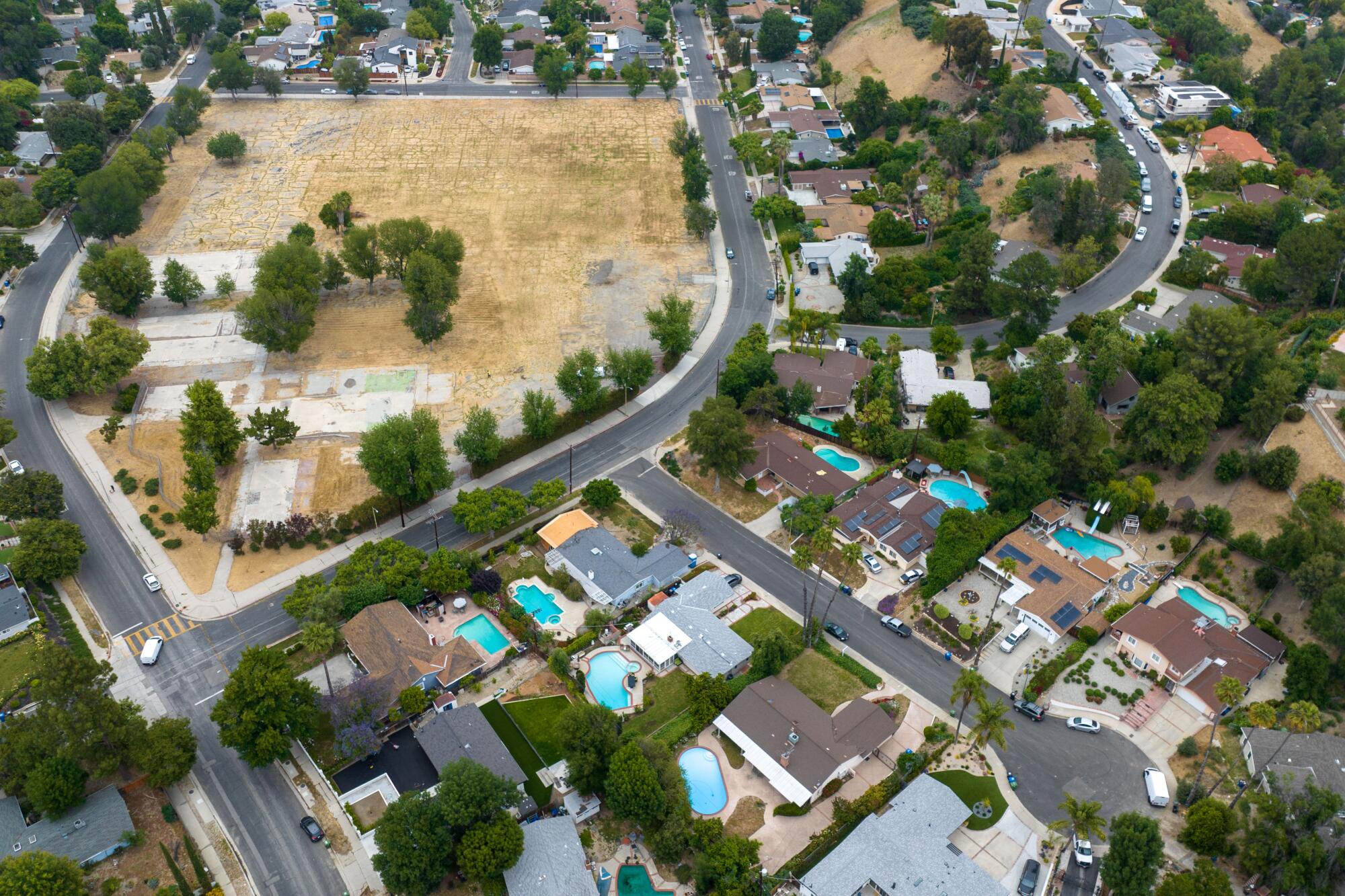 A mostly vacant lot is surrounded by houses in a neighborhood.