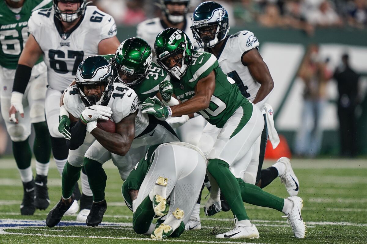 New York Jets' Sharrod Neasman (35) and Michael Carter II (30) tackle Philadelphia Eagles' Kenneth Gainwell (14) during the first half of an NFL preseason football game Friday, Aug. 27, 2021, in East Rutherford, N.J. (AP Photo/John Minchillo)