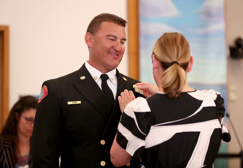 New Fire Chief Niko King smiles as his girlfriend, Brooke Leal, pins his badge to his lapel.