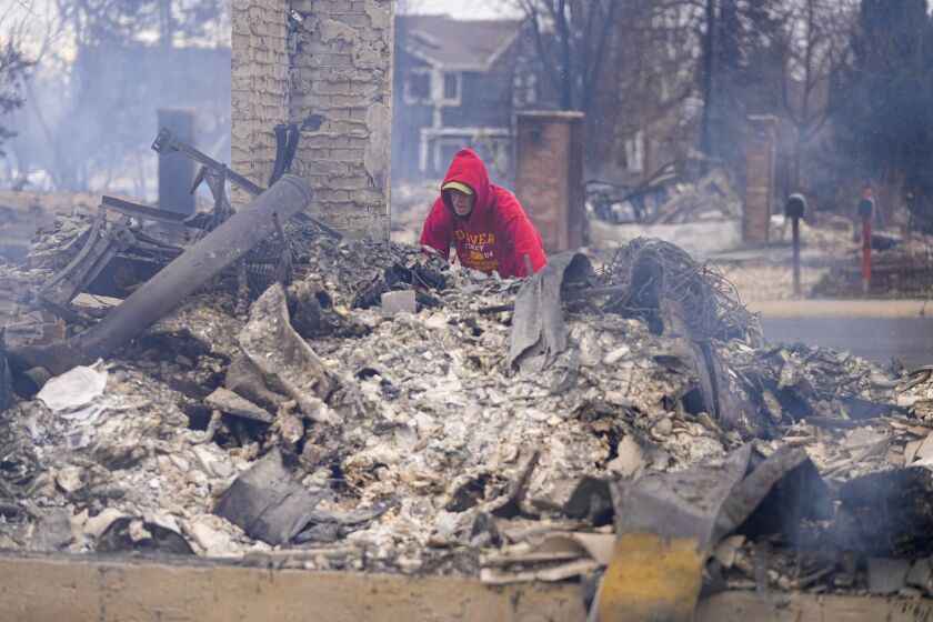 Todd Lovrien looks over the fire damage from the Marshall Wildfire at his sisters home in Louisville, Colo., Friday, Dec. 31, 2021. Tens of thousands of Coloradans driven from their neighborhoods by a wind-whipped wildfire anxiously waited to learn what was left standing of their lives Friday as authorities reported more than 500 homes were feared destroyed. (AP Photo/Jack Dempsey)