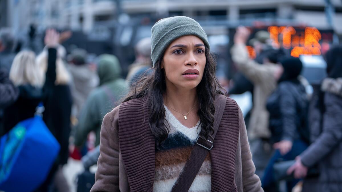 A woman wearing a beanie outside in a city looks scared 