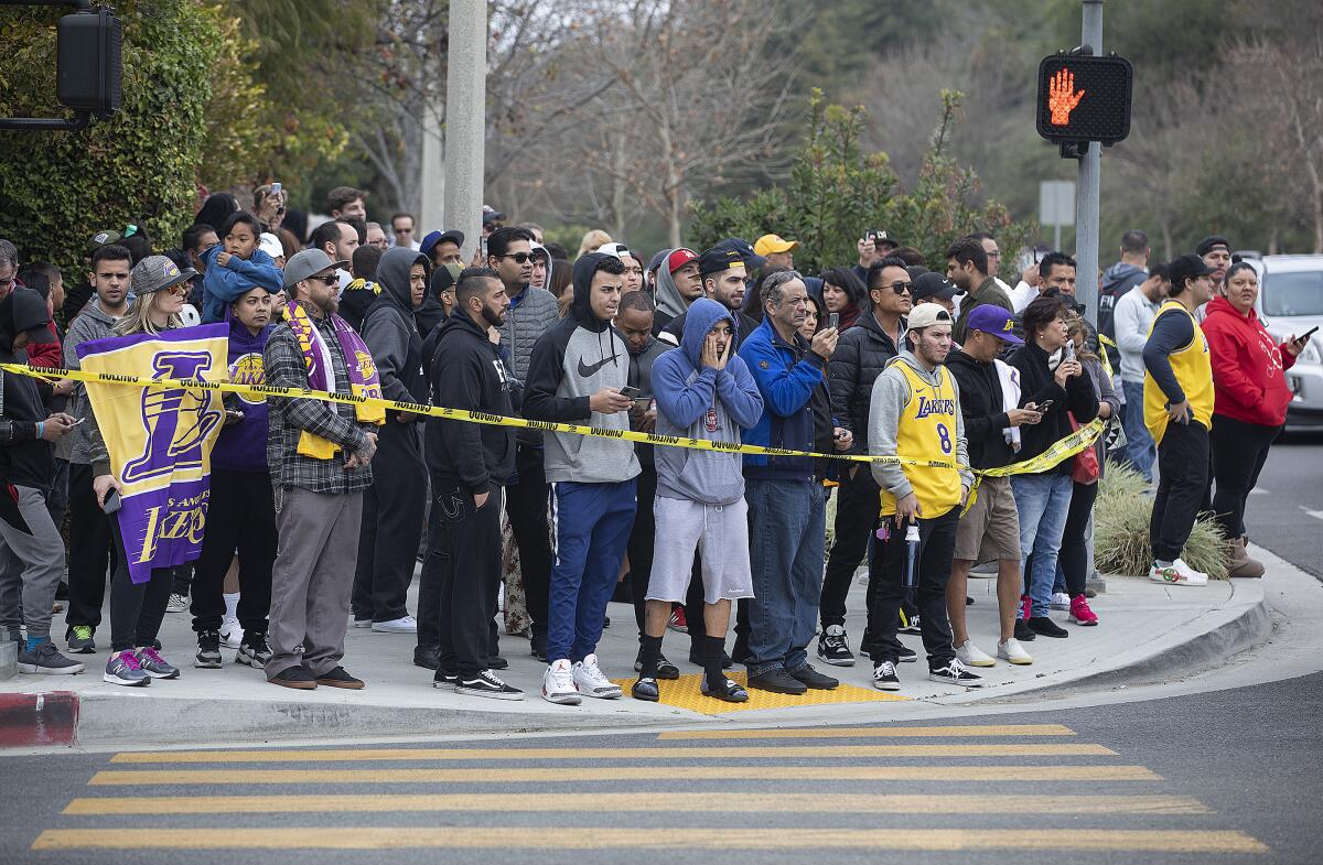 CALABASAS, CA-JANUARY 26, 2020: People gather on Las Virgenes Road in Calabasas near the scene of a helicopter that crashed and burst into flames Sunday morning amid foggy conditions in the hills above. All people aboard were killed including Los Angeles Lakers legend Kobe Bryant. (Mel Melcon/Los Angeles Times)