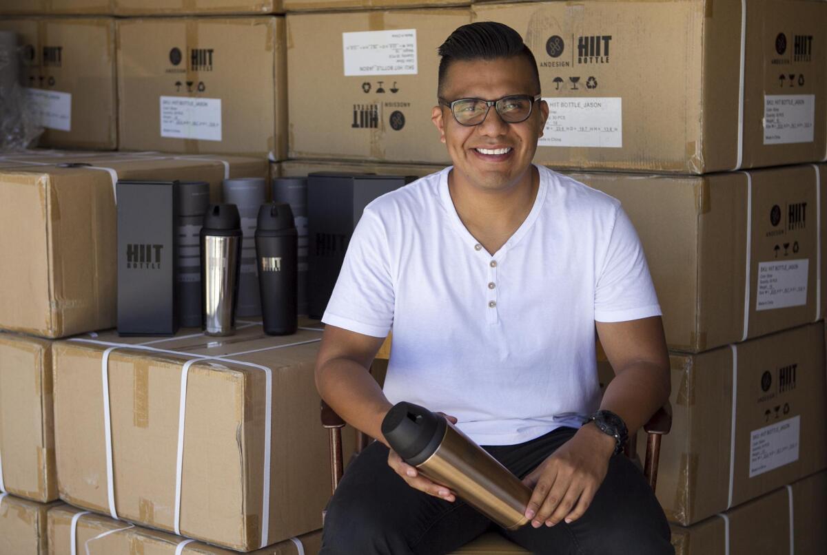 Christian Valencia, 30, sits in a Costa Mesa garage that houses some of his company’s product, the HIIT Bottle, a stainless-steel protein shaker bottle. HIIT stands for high-intensity interval training.
