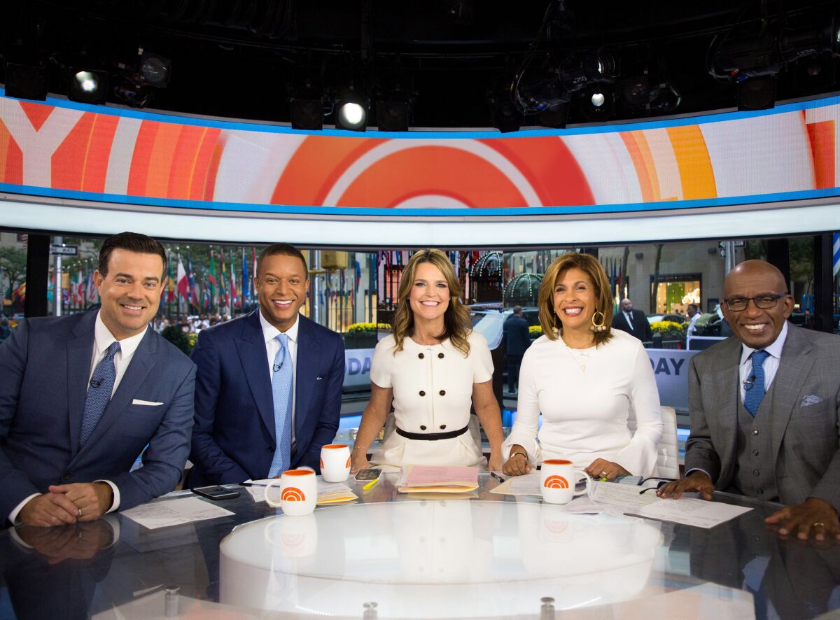 Five people seated at a circular table in a television studio