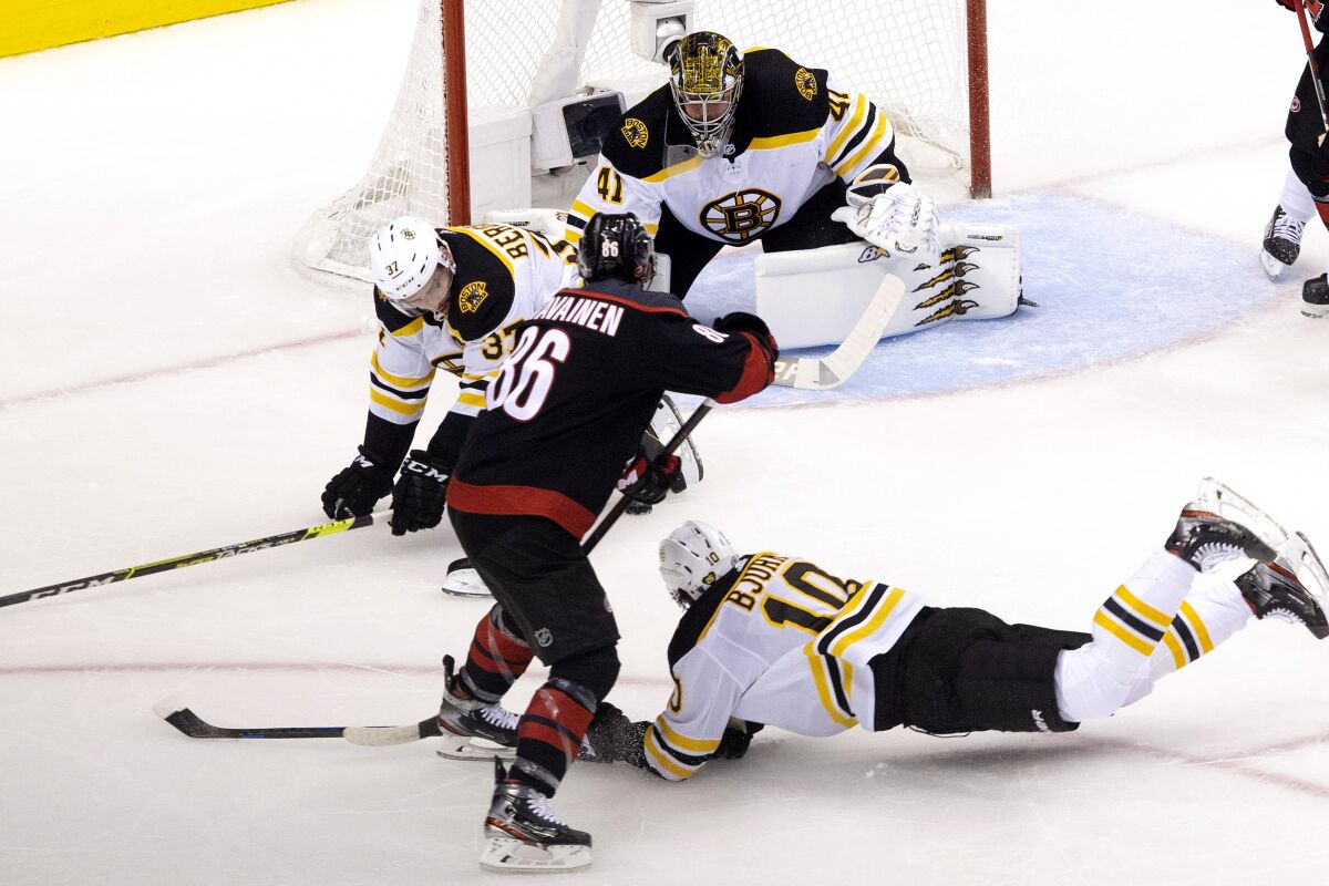 Boston Bruins' Patrice Bergeron (37) and Anders Bjork (10) try to block a shot from Carolina Hurricanes' Teuvo Teravainen (86) as Bruins goaltender Jaroslav Halak (41) looks on during first period NHL Eastern Conference Stanley Cup playoff game in Toronto on Saturday, Aug. 15, 2020. (Chris Young/The Canadian Press via AP)