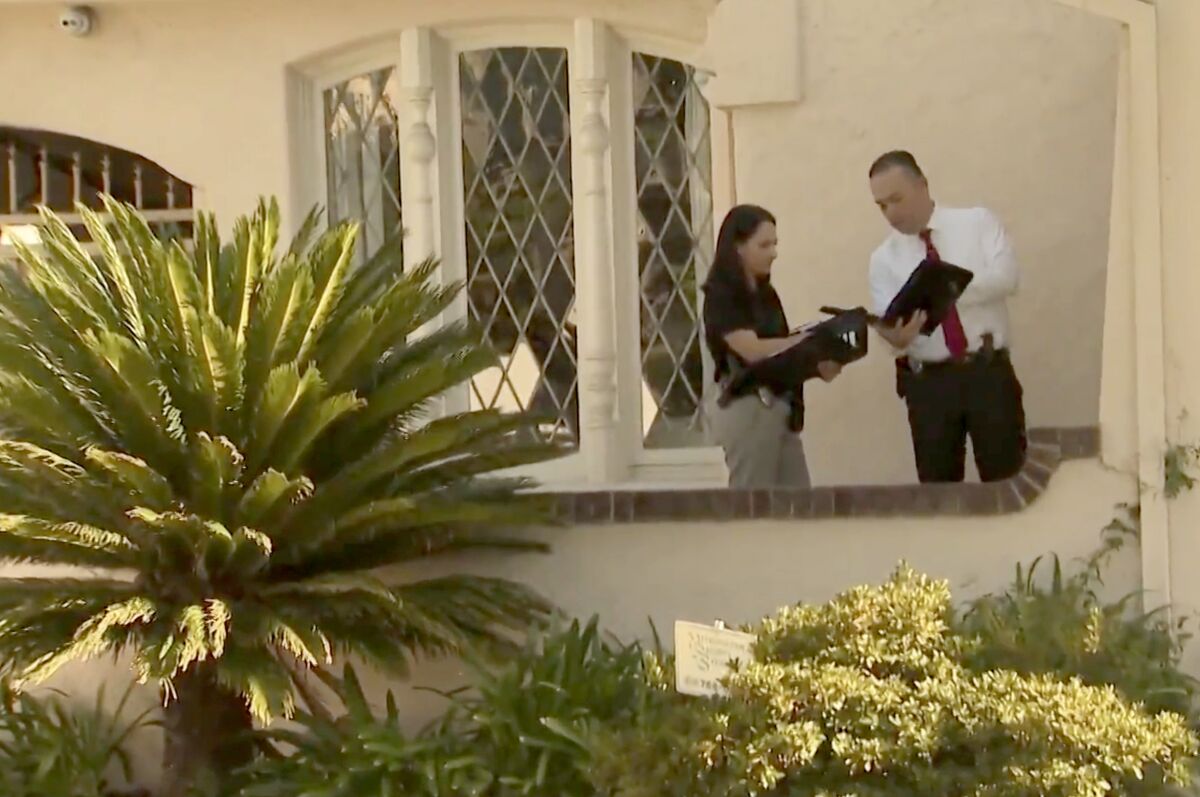 Two investigators are outside a home