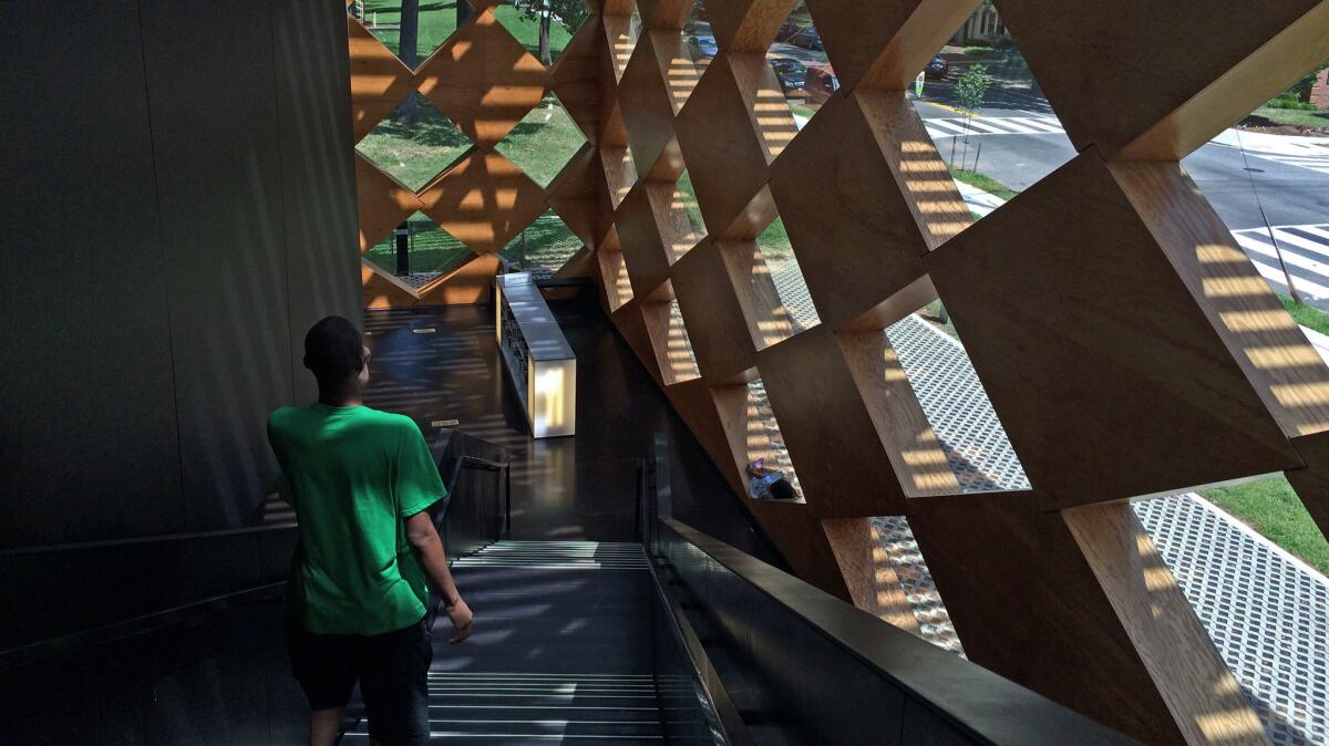 Descending from the second floor to the first — the geometric plywood screen bathes the interiors in dappled light.