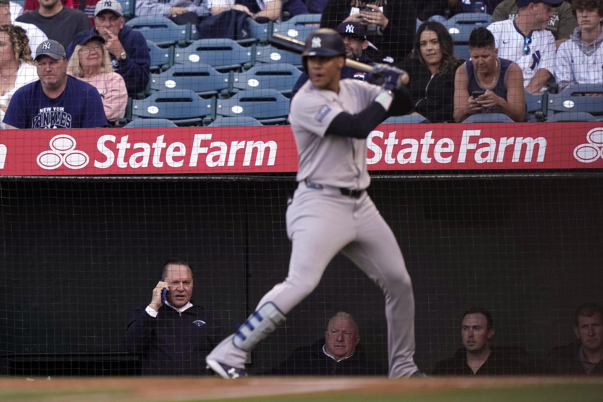 Yankees'in Juan Soto, menajeri Scott Boras'ın (sol altta) telefonda konuştuğu sırada, oyun alanında ısınıyor.