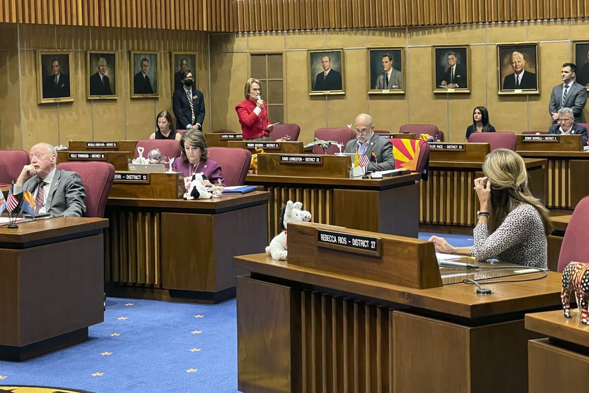 Arizona Republican Sen. Wendy Rogers, standing in the background, defends her inflammatory comments ahead of a censure vote in the Senate on Tuesday, March 1, 2022, at the state Capitol in Phoenix. The Senate voted 24-3 to censure Rogers, whose embrace of white nationalism and calls for violence drew condemnation from across the political spectrum. (AP Photo/Jonathan J. Cooper)