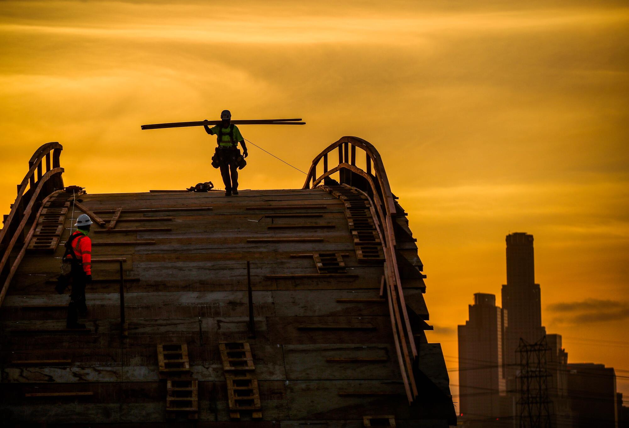 People work on the 6th Street bridge at sunset.