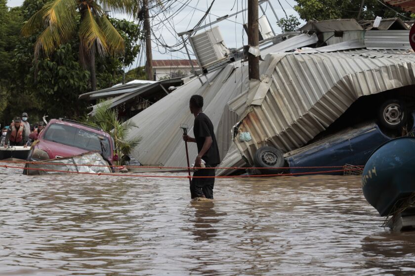 FILE - In this Nov. 6, 2020, file photo, a resident walking through a flooded street looks back at storm damage caused by Hurricane Eta in Planeta, Honduras. Environmental campaigners called Wednesday for fossil fuel producers to contribute to a new fund intended to help poor countries cope with climate disasters. (AP Photo/Delmer Martinez, File)