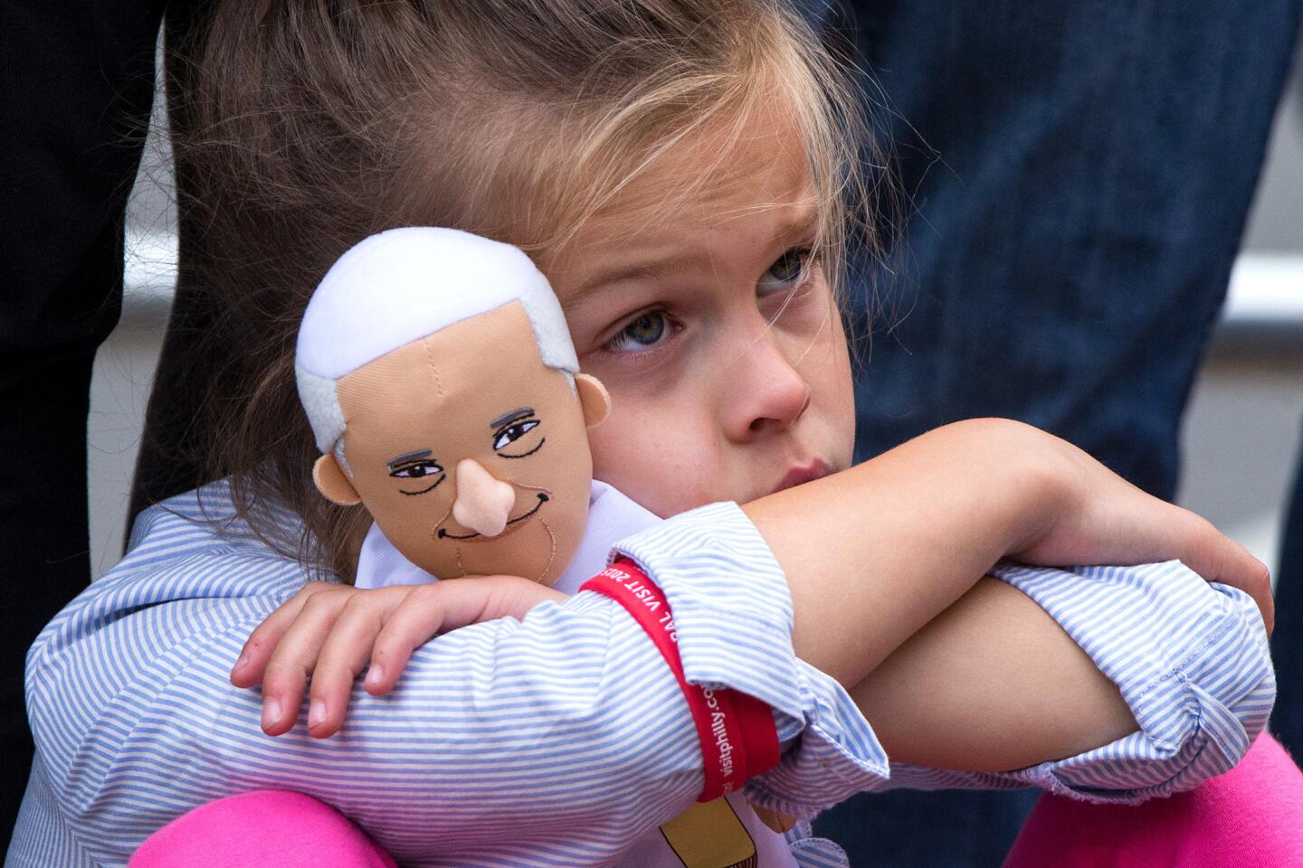Seven-year-old Leyla Drees of Stewartville, Minn., clings to her Pope Francis doll while watching the pope's speech on immigration on a giant monitor at JFK Plaza in Philadelphia on Saturday, Sept. 26, 2015.