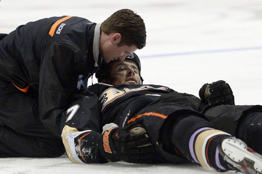 A Ducks team trainer assists left wing Dustin Penner after he was briefly knocked unconscious on a hit by Dallas Stars forward Ryan Garbutt during Sunday's game.