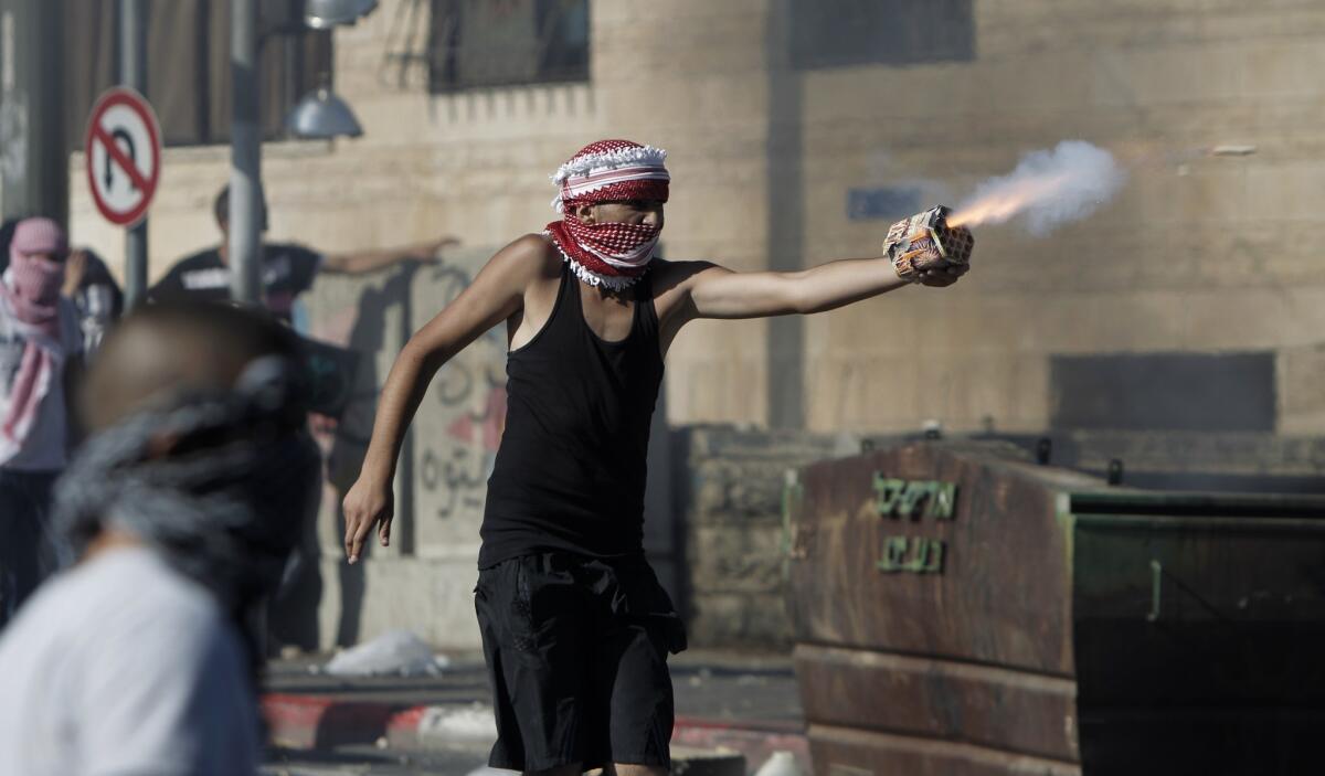 A Palestinian protester directs fireworks toward Israeli police during clashes in East Jerusalem following news of a feared reprisal killing for the deaths of three kidnapped Israeli youths.