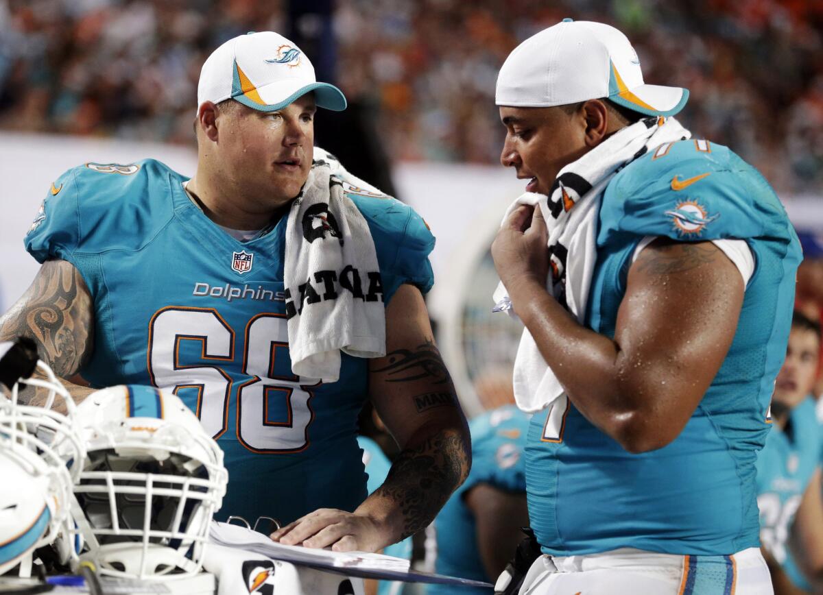 Miami Dolphins guard Richie Incognito (68) and tackle Jonathan Martin (71) look over plays during an NFL preseason football game against the Tampa Bay Buccaneers in Miami Gardens, Fla.