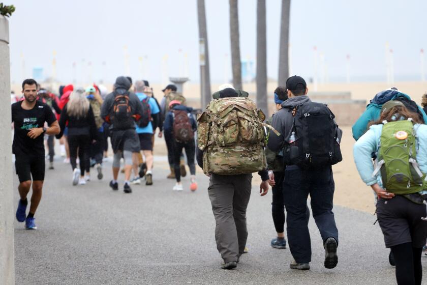 About 100 people take part in the "ruck march" to bring awareness to the statistic that 22 veterans die by suicide a day, each participant is carrying 22 pounds of weight representing 22 veterans that die a die, the "ruck march" started at Huntington Beach pier on Saturday, March 23, 2024. (Photo by James Carbone)