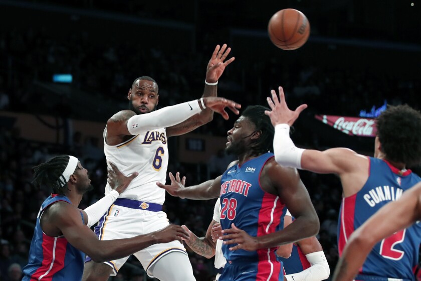 Los Angeles Lakers forward LeBron James, second form left, passes the ball away from Detroit Pistons forward Jerami Grant, left, and center Isaiah Stewart (28) during the first half of an NBA basketball game Sunday, Nov. 28, 2021, in Los Angeles. (AP Photo/Alex Gallardo)