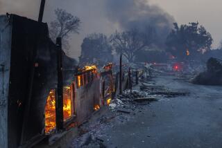 Homes smolder to ashes as an apartment burns in the background during the Eaton fire.