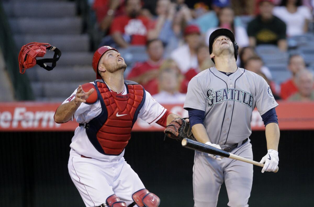 Angels catcher Chris Iannetta and Seattle's Mike Zunino watch his bunt attempt pop up in the third inning Friday night. Zunino was called out for interference on the play.