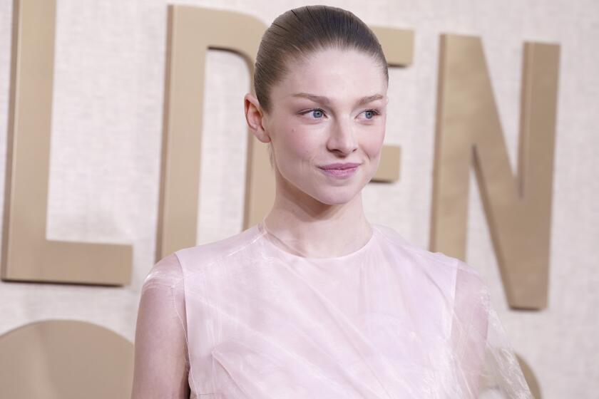 Hunter Schafer poses in a pale sleeveless gown with her hair pulled back