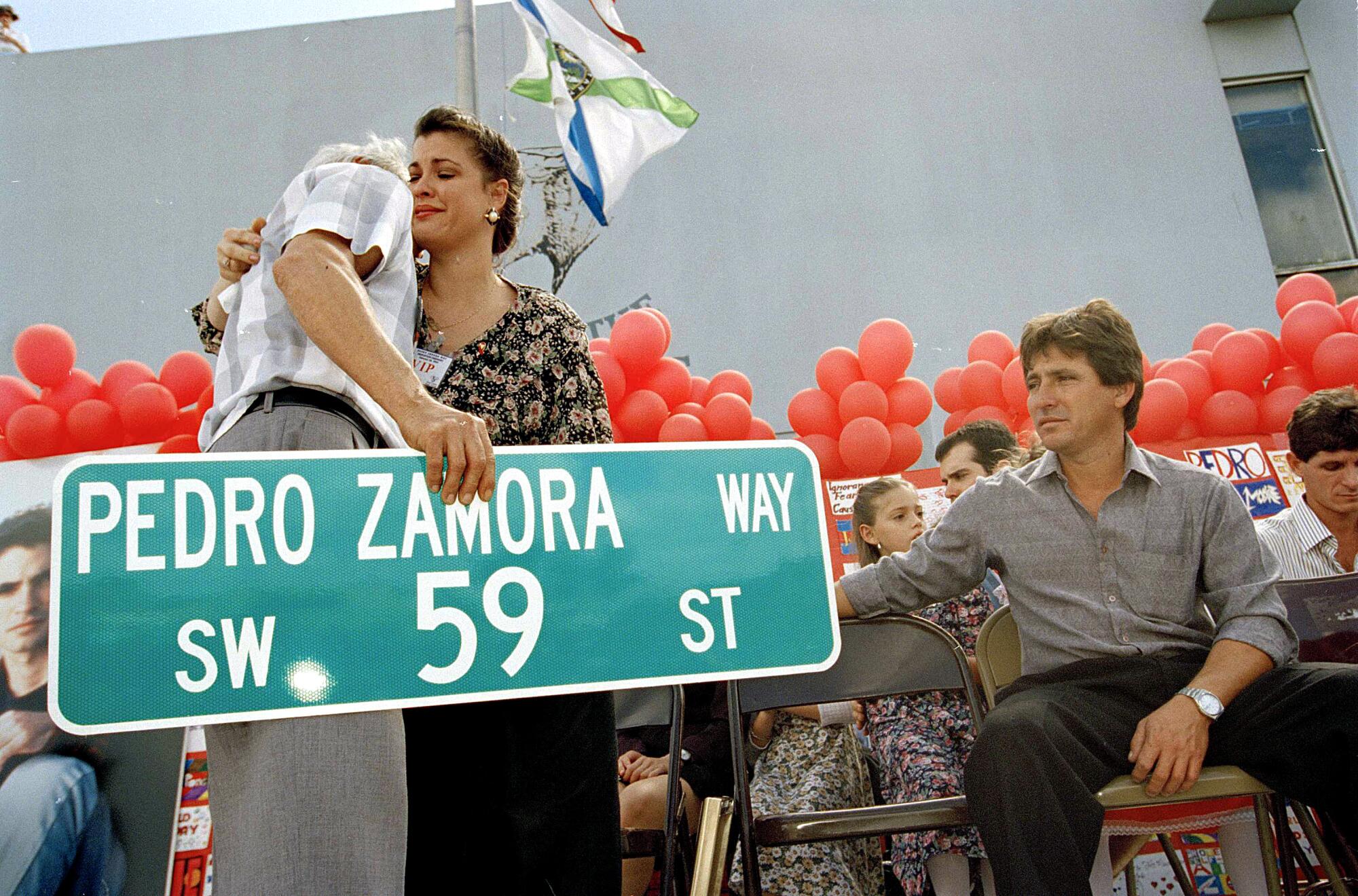 The sister of late AIDS activist Pedro Zamora, hugs her father after a street is named Pedro Zamora Way.