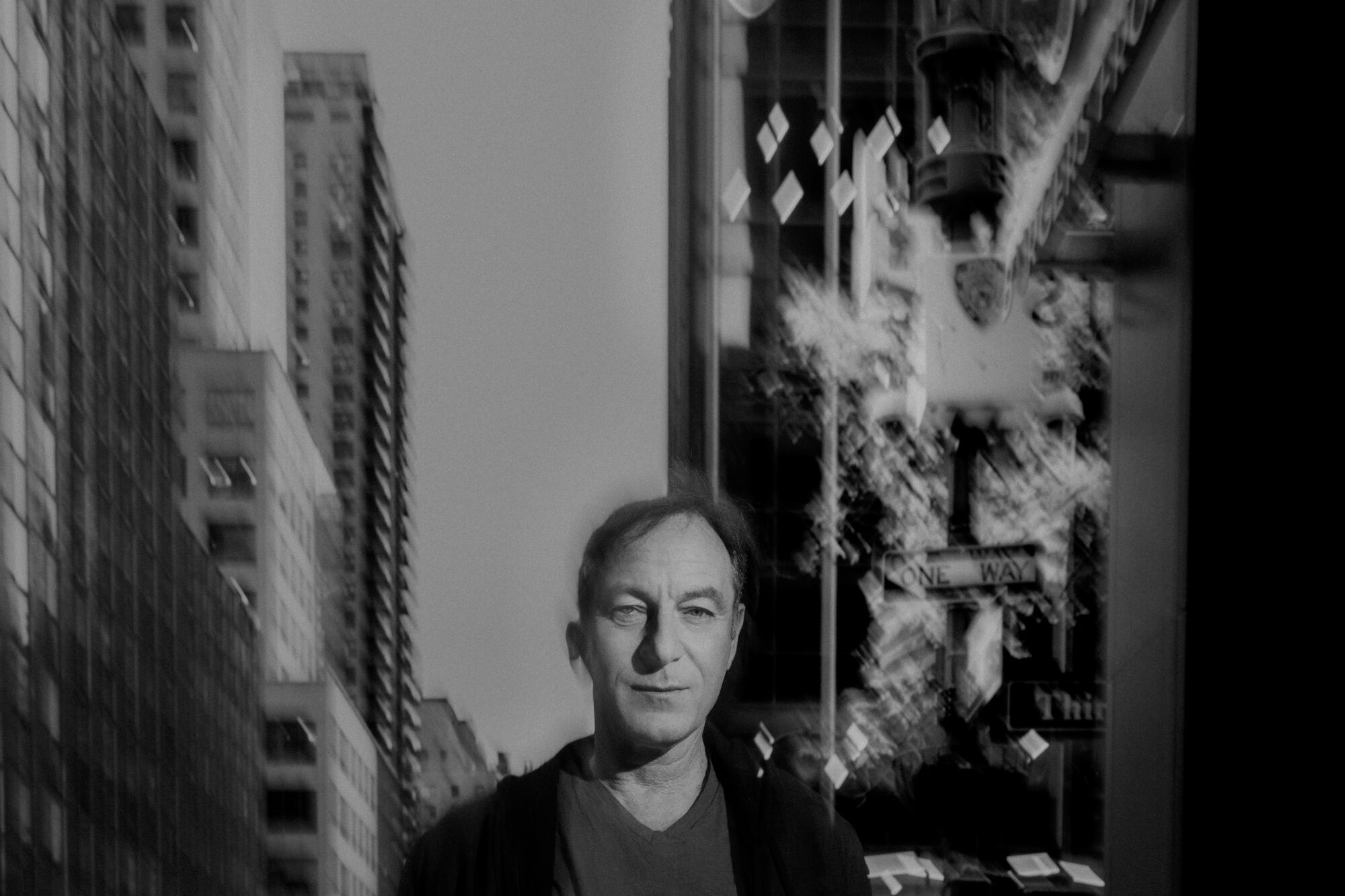 A black-and-white photo of a man on a street in New York City, tall buildings behind him.