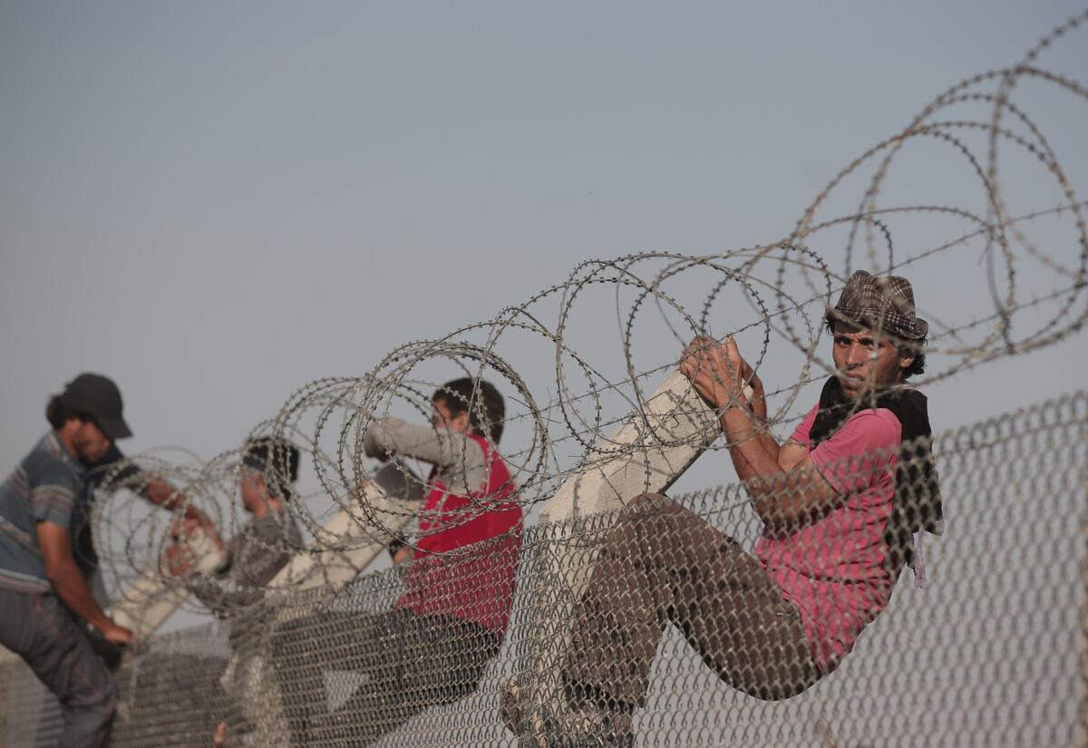 Syrian refugees climb a border fence from Syria to Turkey in Akcakale, southeastern Turkey, on June 14.
