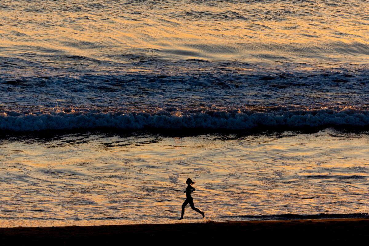 A jogger takes a sunset run on a beach.