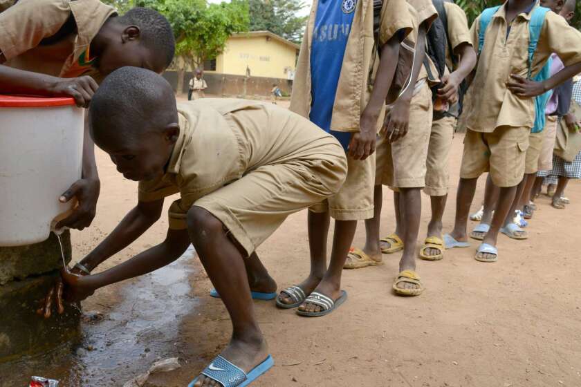 Children wait in line to wash their hands on Oct. 23 at a school in Bouake, Ivory Coast, which is currently free of the Ebola epidemic ravaging its neighbors and has launched a hunt for a Guinean health worker who may have fled his home country after possibly catching the disease.