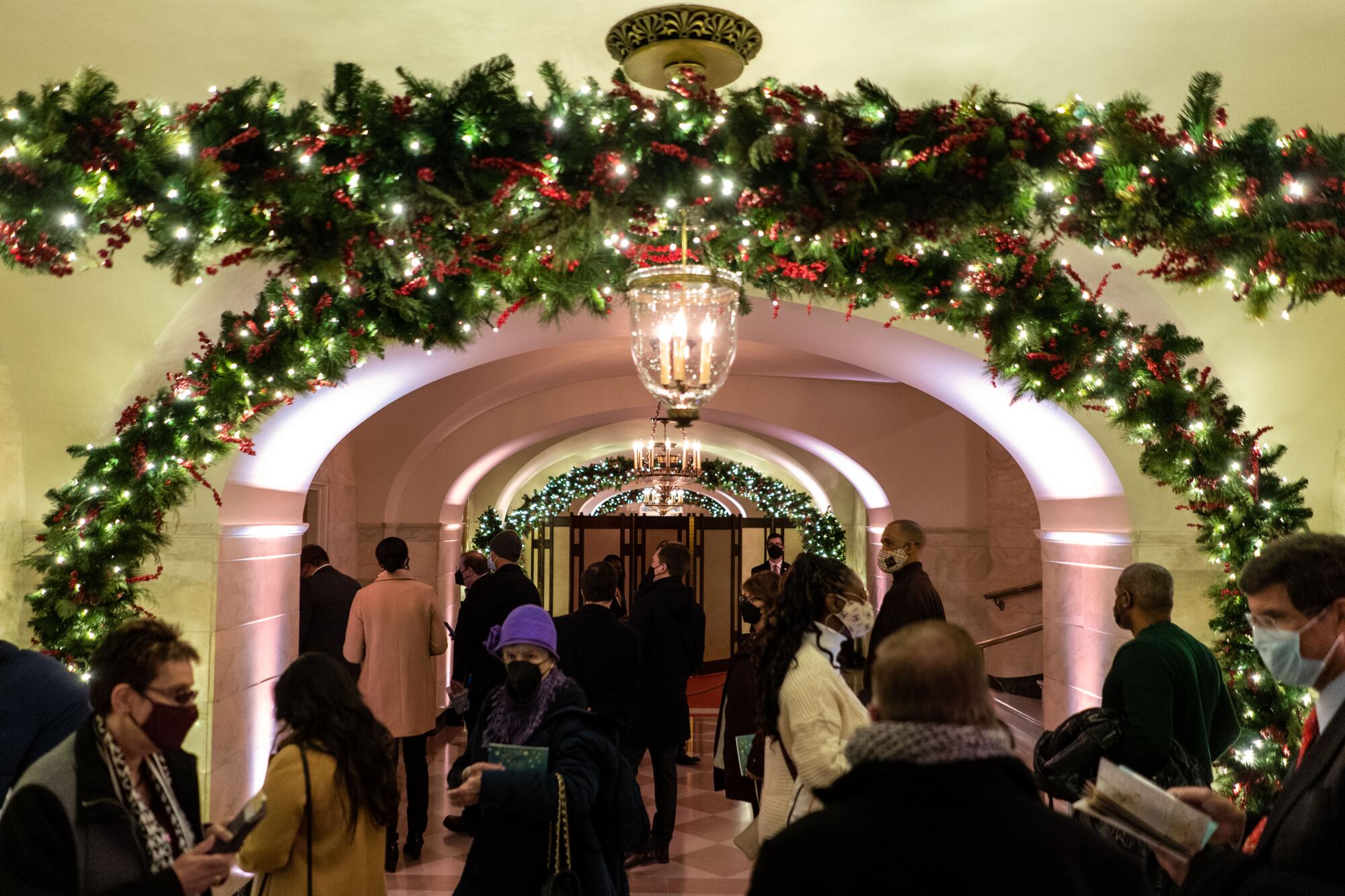 Members of the public wander the center hall of the White House during a Christmastime tour.