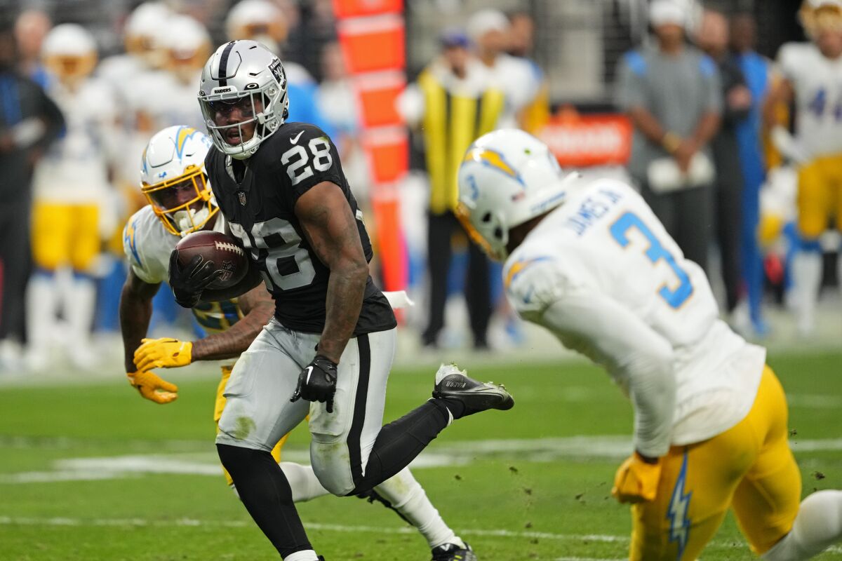 The Raiders' Josh Jacobs (28) runs for a touchdown as Chargers safety Derwin James Jr. (3) pursues.
