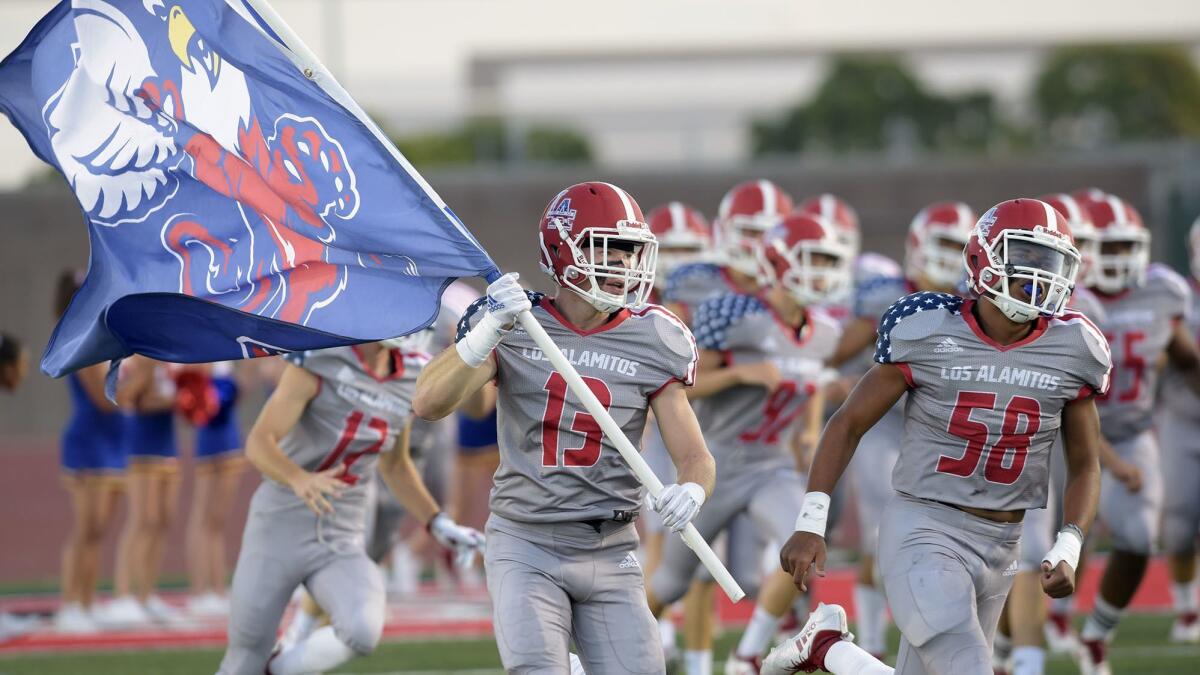Los Alamitos High's Dallas Burke (13), shown carrying the team flag before a game against Wilmington Banning on Sept. 6, had two interception returns for touchdowns in the Griffins' 47-0 shutout of Huntington Beach on Oct. 19.