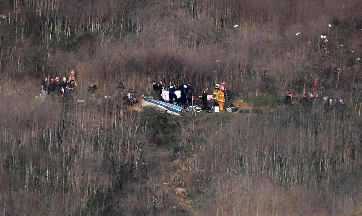 Officials remove a body from the wreckage of the helicopter crash Sunday in Calabasas.