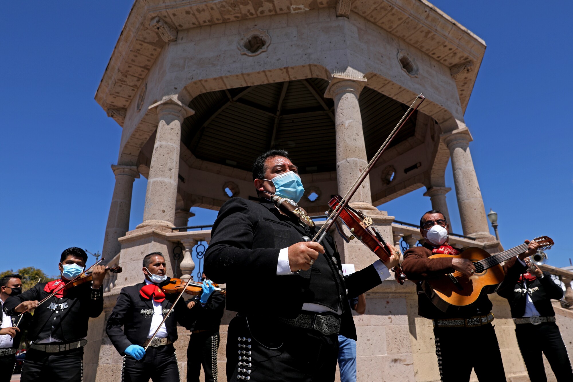 Israel Moreno, center, Jose Cervantes, right, and other musicians join in solidarity at Mariachi Plaza in Boyle Heights to ask local officials for financial help during the pandemic.