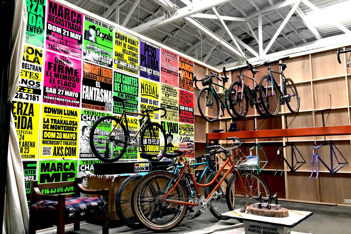Bikes on display in a warehouse space with one wall decorated in colorful lucha libre posters