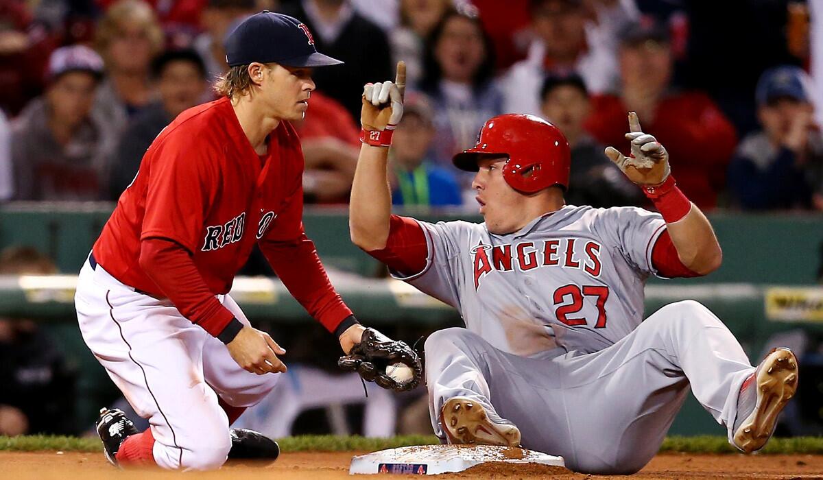 Angels' Mike Trout slides safely into third past Boston Red Sox's Brock Holt during an Angels 12-5 rout over the Red Sox on Friday.